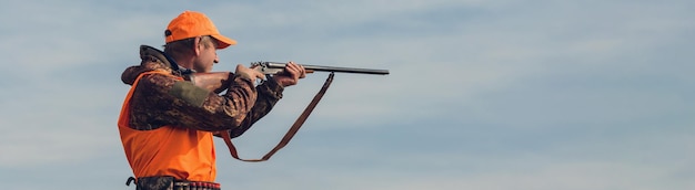 Pheasant hunter with shotgun walking through a meadow