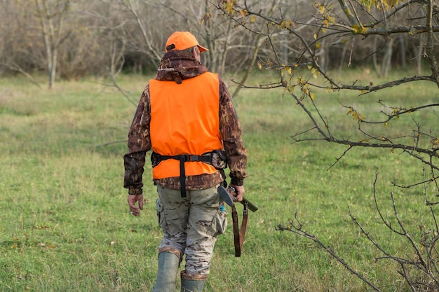 Pheasant hunter with shotgun walking through a meadow
