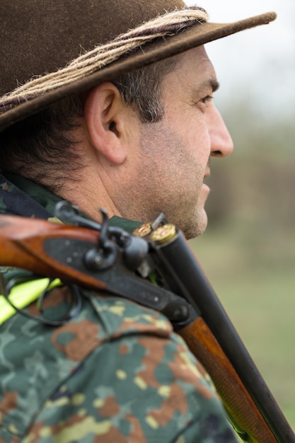 Pheasant hunter with shotgun walking through a meadow