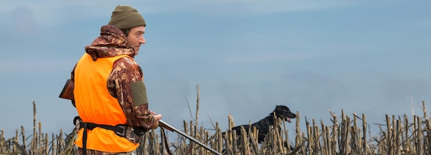 Pheasant hunter with shotgun walking through a meadow