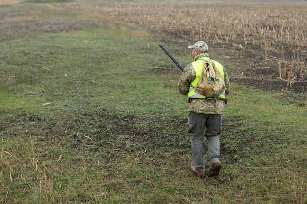 Pheasant hunter with shotgun walking through a meadow