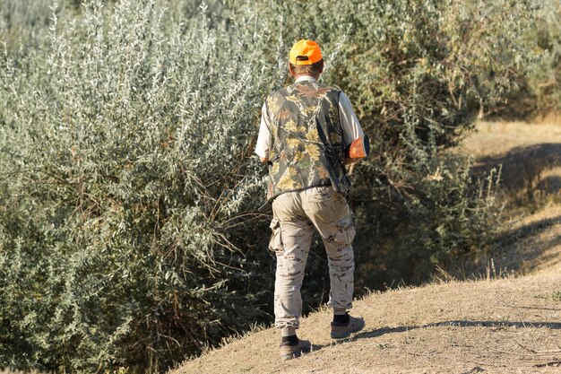 Pheasant hunters with shotgun walking through a meadow.