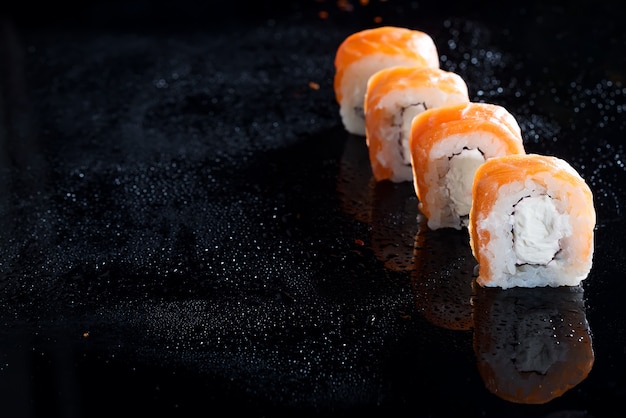 Philadelphia roll classic on black glass background. Japanese sushi food. 