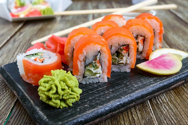 Филадельфия ролл суши с лососем, креветками, авокадо, сливочный сыр подается на деревянном фоне. Суши-меню. Японская еда. Суши