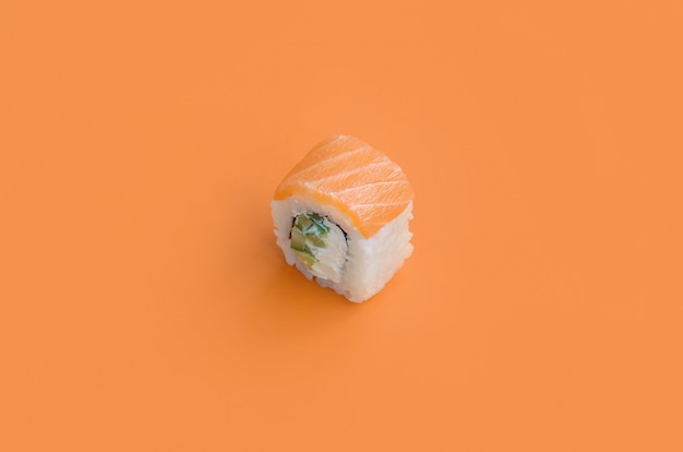 Philadelphia roll with salmon on orange background. Minimalism top view flat lay with Japanese food