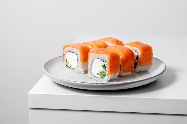 Philadelphia rolls with salmon fish, cucumber and cheese on plate on white background