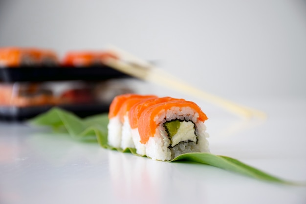 Philadelphia sushi with salmon, avocado and cheese on green leaf