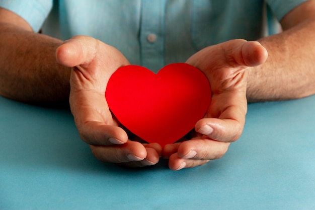 Philanthropy and charity concept. Hands offering a paper heart. Selective focus.