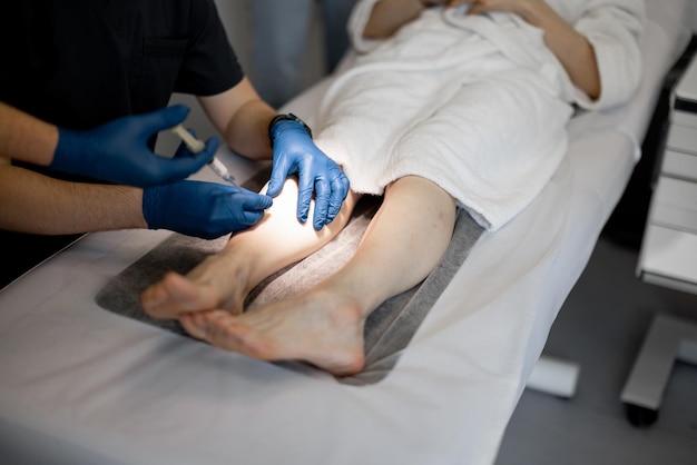 Photo phlebologist performs sclerotherapy on the veins of womens leg