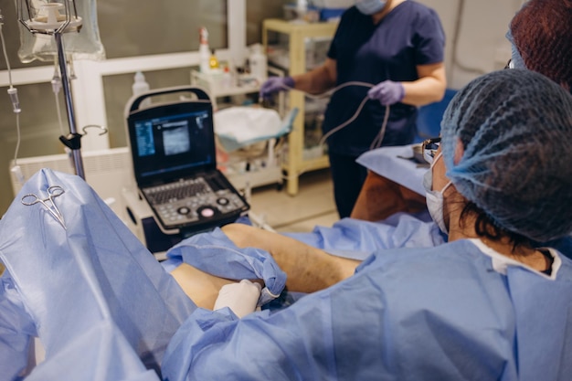 A phlebologist performs an ultrasound of the legs for varicose veins using a modern