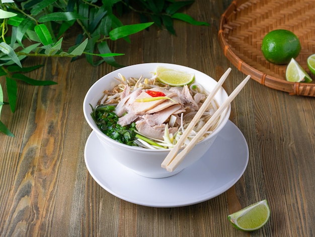 Pho bo pittige bouillon of soep in witte keramische kom met plakjes rijstnoedels en kruidenconcept Vietnamees eten