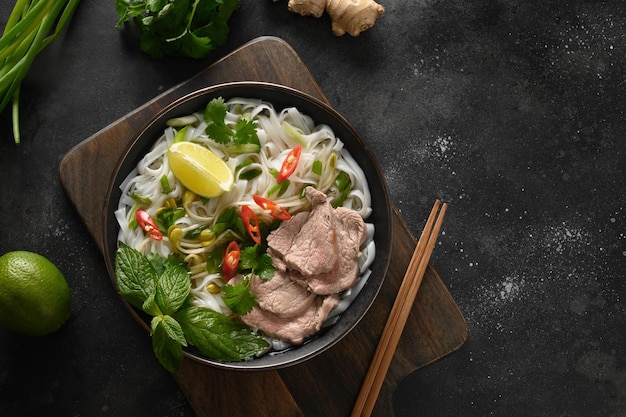 Pho Bo Soup with beef in bowl on black background Vietnamese cuisine