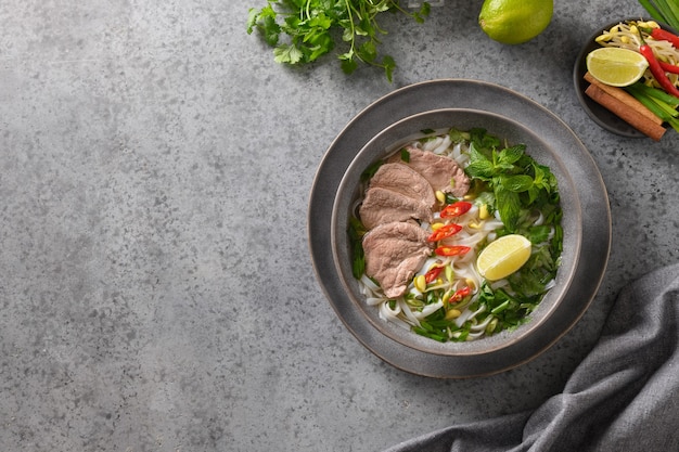 Pho bo soup with beef in gray bowl on gray vietnamese cuisine