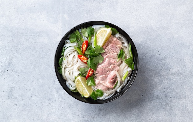 Pho bo vietnamese soep met rundvlees en rijstnoedels op een concrete achtergrond, bovenaanzicht