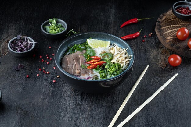 Pho Bo vietnamese Soup with beef on dark background Top view