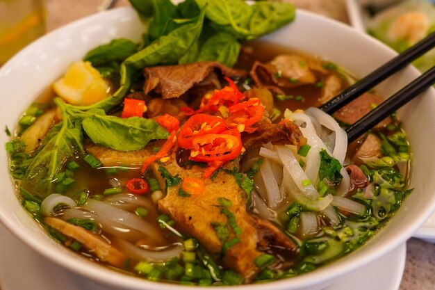 Foto pho bo o zuppa vietnamita con manzo e polpette di carne servite in una ciotola bianca al ristorante