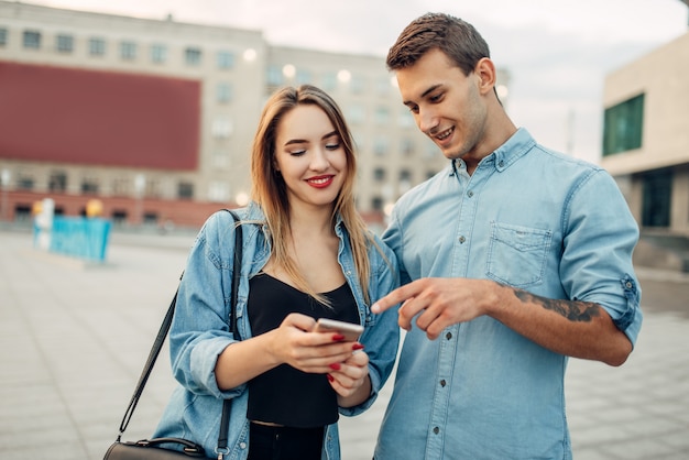 Phone addiction, addict woman shows her social page to young man. Addicted people, modern relationship