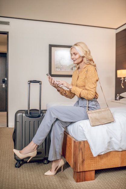 On the phone. Blonde elegant woman with a smartphone in hands