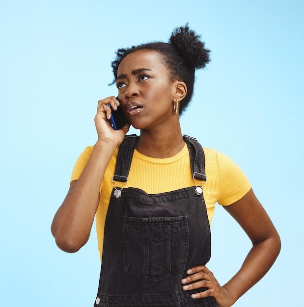 Phone call confused and black woman on blue background with spam problem network and connection Communication advertising and girl in conversation talking and scam with smartphone in studio