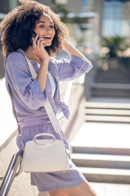 電話。電話で話しているかわいい若い巻き毛の女性