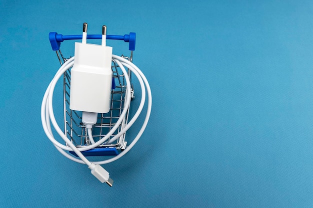 A phone charger in a supermarket cart on a blue background