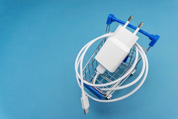 A phone charger in a supermarket cart on a blue background