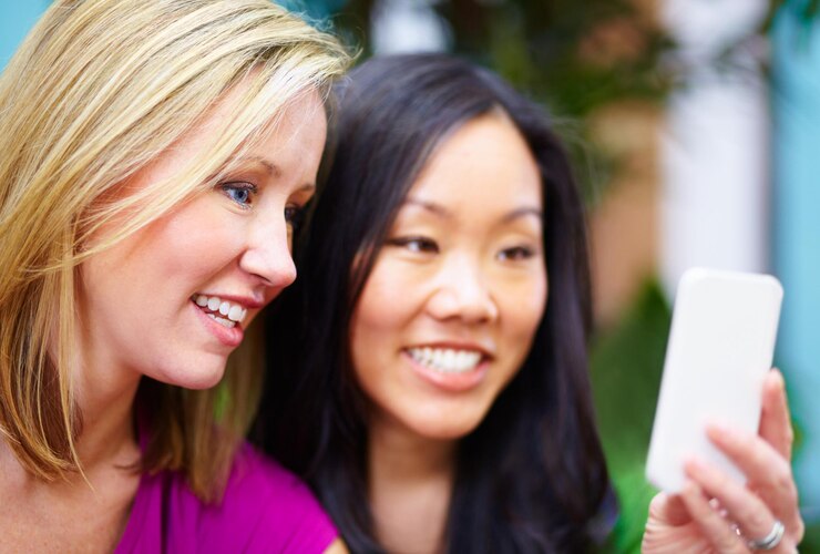 Photo phone gossip and friends on social media internet and share meme in an outdoor park together chatting on an app technology happy and young people or women search the web website on a smartphone