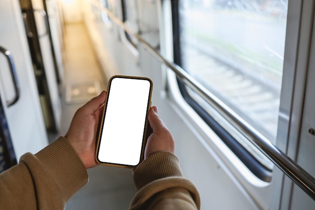 電車のキャビンの背景に孤立した画面で手に電話をかける