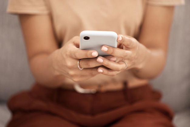 Phone hands and woman texting closeup on a sofa social media or online chatting in a living room Zoom hand and girl internet search browsing or checking news update meme or post in her home