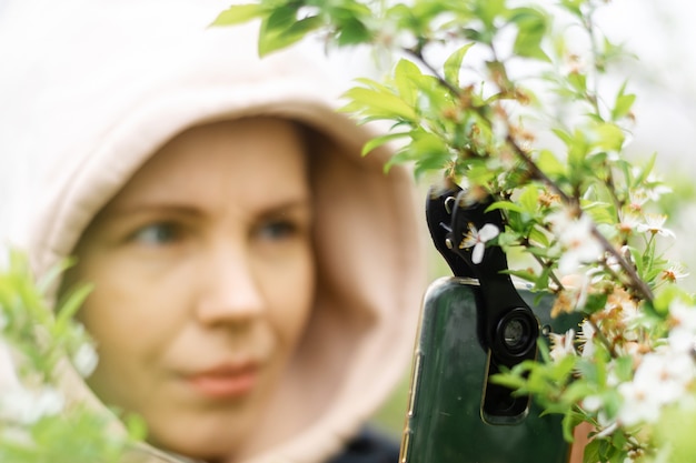 매크로 사진용 폰 렌즈. 한 여성이 매크로가 부착된 휴대전화를 손에 들고 식물 사진을 찍고 있습니다.