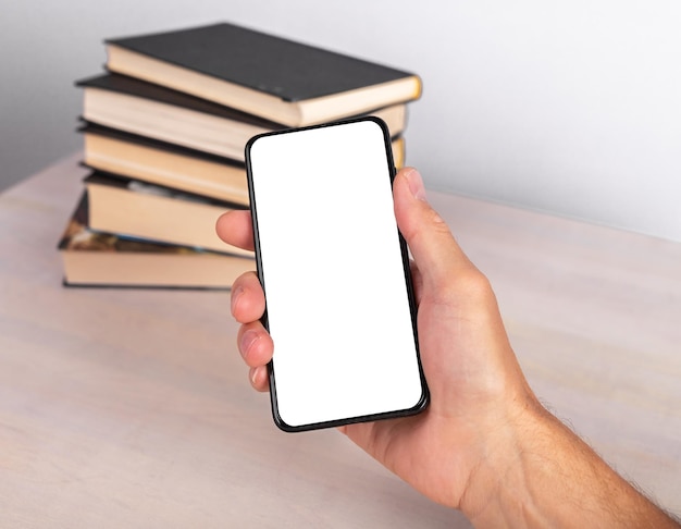 Phone mockup for mobile app for reading ebooks and study online advertising Hand holding smartphone with blank screen near books stack