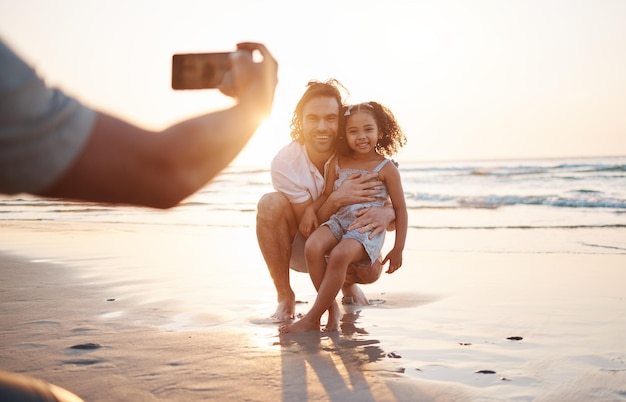 Phone photography father and daughter at beach sunset sky and happy for memory holiday and bonding Smartphone profile picture and man with girl child hug and care for post social media and sea