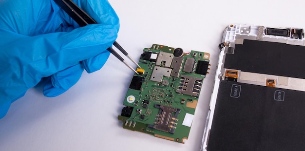 A phone repairman checks the mobile phone board on a white background