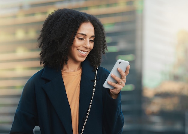 Phone social media and communication with a business black woman typing a text message in the city Mobile networking and contact with a happy female employee reading an email in an urban town