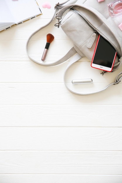 Phone, stylish bag and perfumes on white background. Beautiful flat lay. Things for business woman. Note book schedule. Makeup kit. Girl's gift with hearts.