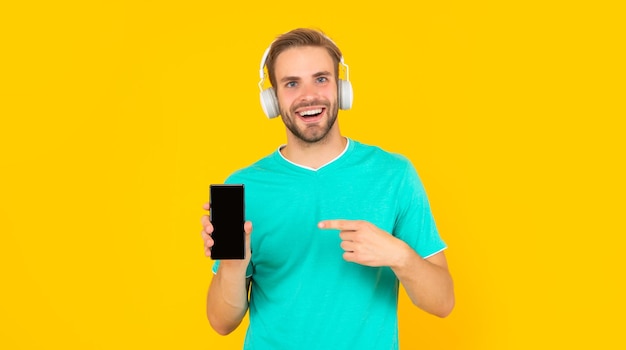 Phone that always keeps you happy Happy guy pointing at mobile phone Music smartphone