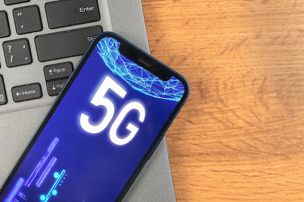 Telefono con rete 5g. sfondo del desktop aziendale. foto concettuale di internet ad alta velocità, nuova generazione di reti, dati e connessione, ologramma sullo schermo ravvicinato