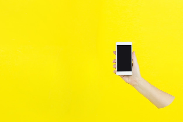 Phone with a black screen in hand. cropped shot hand holding smartphone with blank screen on yellow