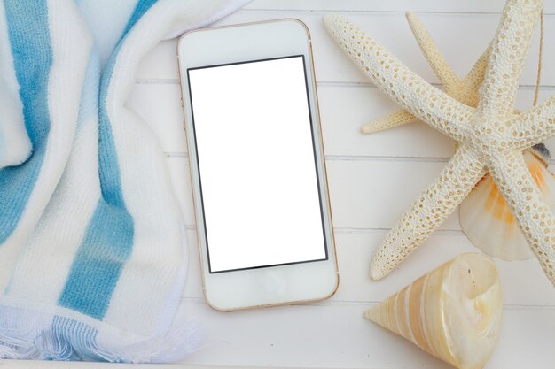 Phone with blaue beach towel and seashells on white background