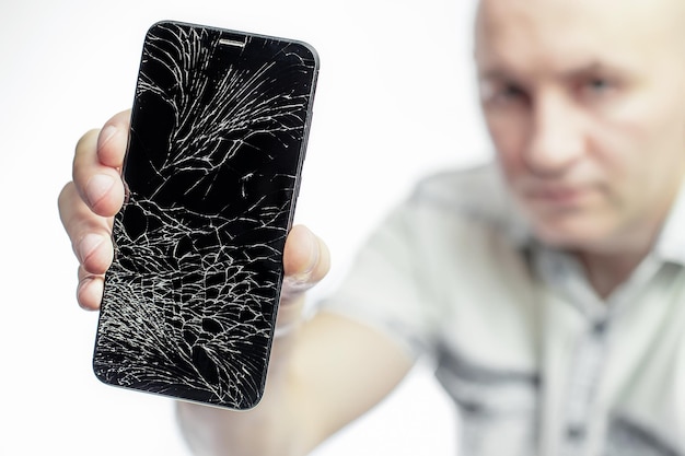 Photo phone with a broken screen closeup a white man is holding a black smartphone with a cracked display