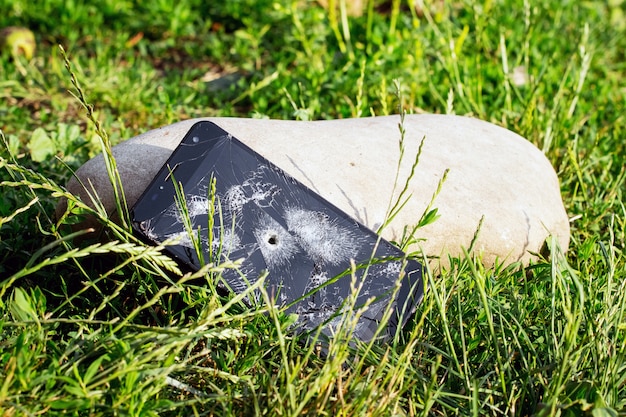 Foto un telefono con un touch screen rotto e un buco da un proiettile