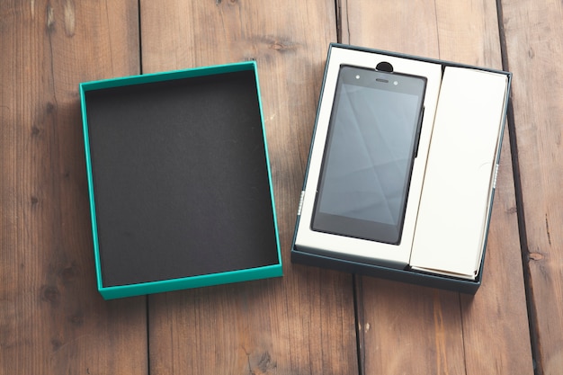 Phone with green-black box on wooden table