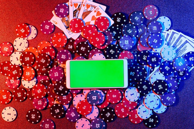 Фото Телефон с зеленым экраном и игрой в покер на спине на столе с красными и синими огнями