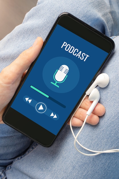 The phone with the podcast turned on lies in a woman's hand against the background of jeans. Concept of internet broadcasts on different topics.