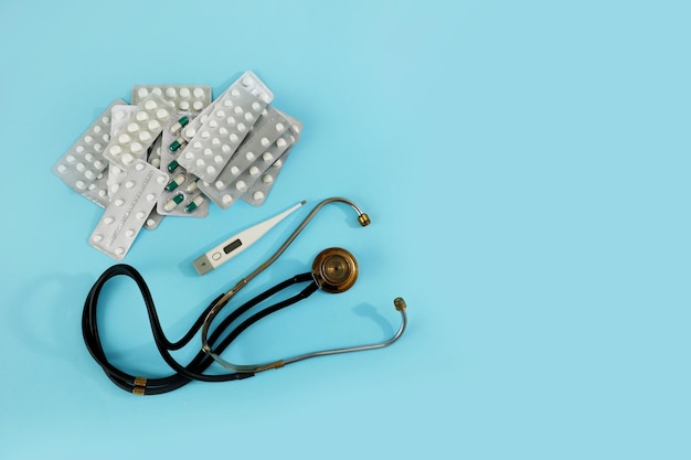 Phonendoscope thermometer and pills on a blue background medical background with copy space