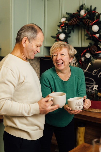 Photo of 60s elderly couple enjoying life at the kitchen with mugs of coffee. st valentines day of