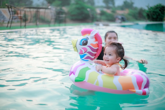 Photo of adorable little girl with mom Colorful unicorn inflatable ring swimming in a tropical ocean on summer vacation High quality photo copy space for text