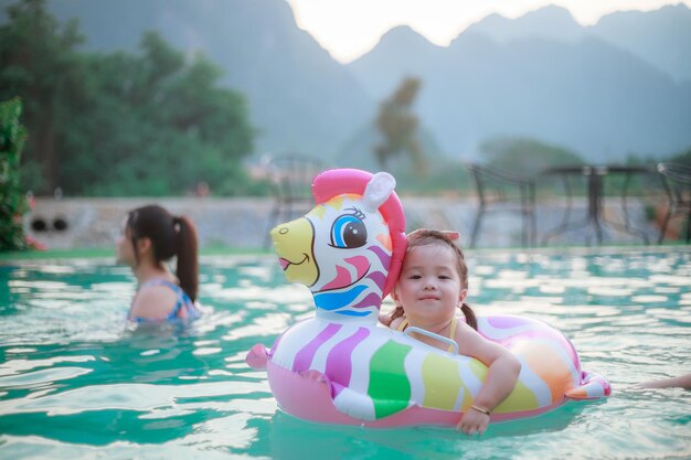Photo of adorable little girl with mom Colorful unicorn inflatable ring swimming in a tropical ocean on summer vacation High quality photo copy space for text