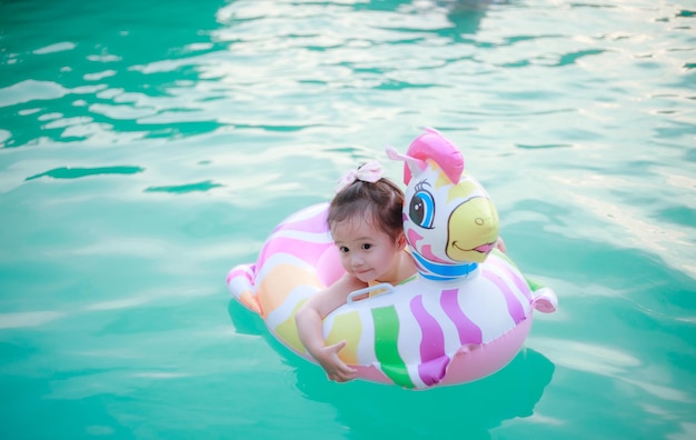 お母さんと愛らしい女の子の写真夏休みに熱帯の海で泳いでいるカラフルなユニコーンのインフレータブル リングテキスト用の高品質の写真コピー スペース