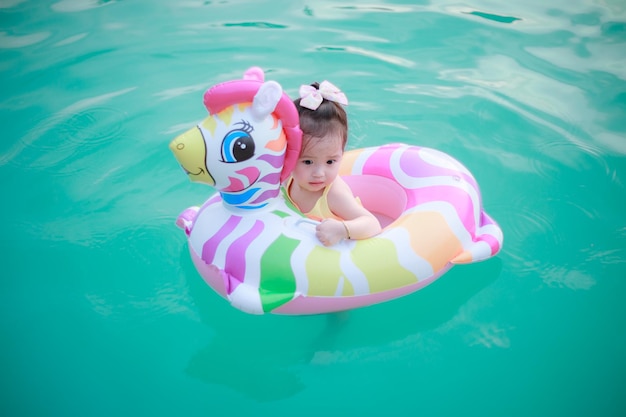 Photo of adorable little girl with mom Colorful unicorn inflatable ring swimming in a tropical ocean on summer vacation High quality photo copy space for text